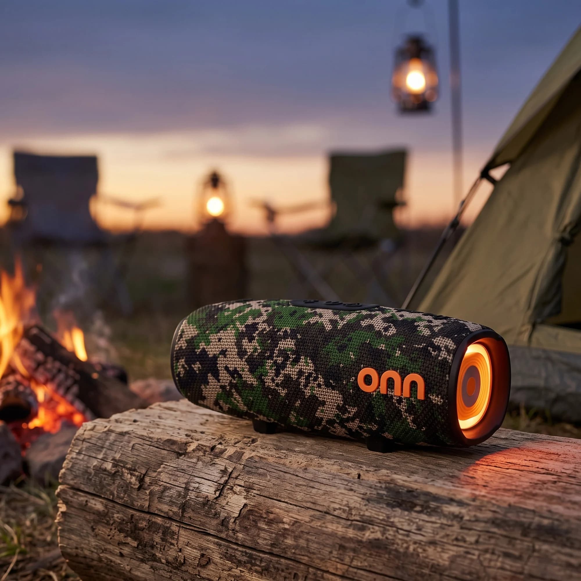onn. camo rugged speaker glowing orange on a log beside a campfire at dusk, with lanterns and a tent behind it
